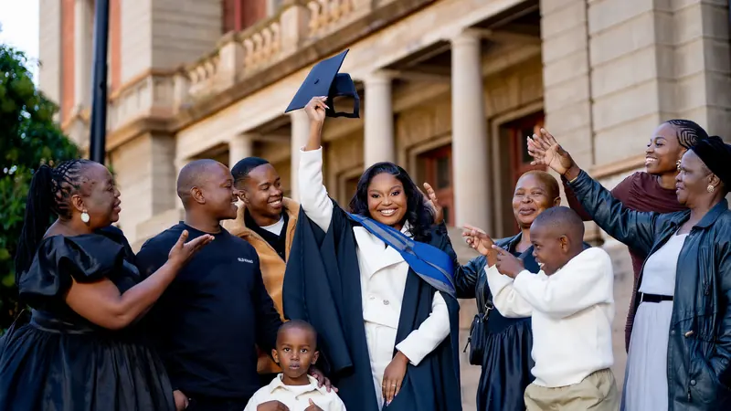 Elaine celebrating her graduation with family and friends outside a university building